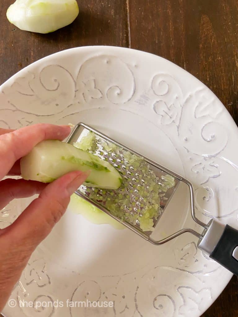 Grate cucumbers into a bowl.
