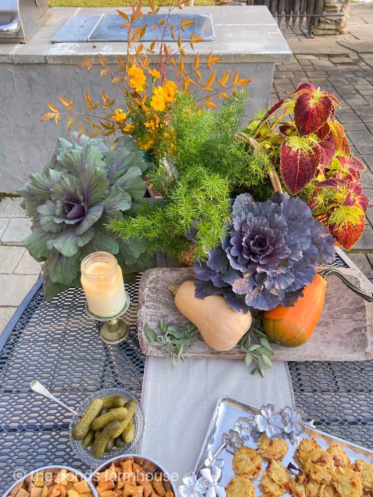 A Fall Table Centerpiece using fall plants and gourds, pumpkins for an alfresco dinner party.