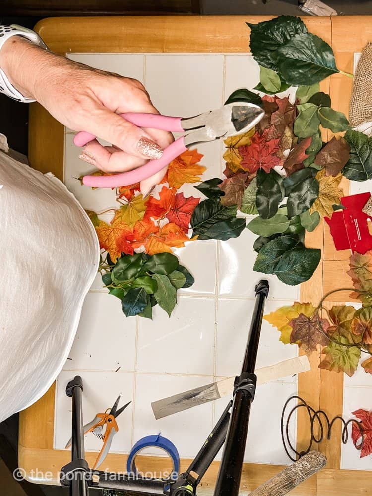 Snip stems from artificial fall leaves to recycle.