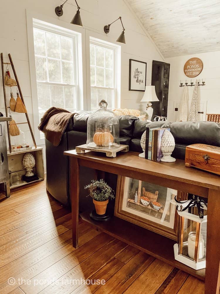 Fall Decorations in loft sofa table with lower shelf filled with fall decor.  