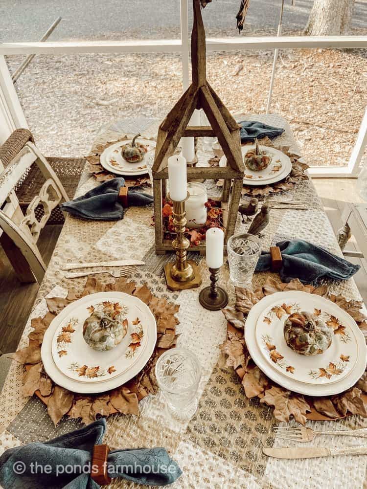 rustic tablescape with fall leaves plate chargers and tobacco stick lantern for centerpiece