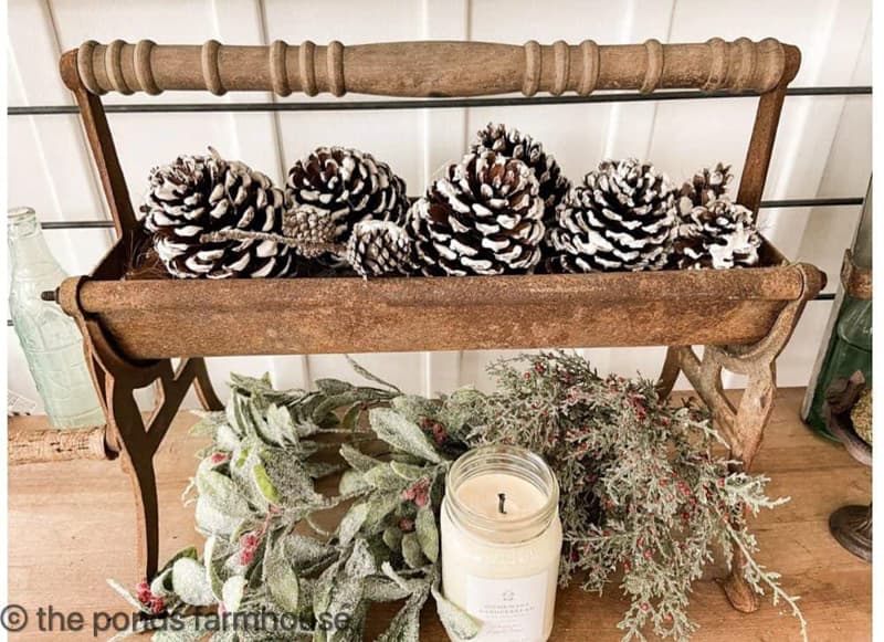 Antique Paper roller filled with flocked pinecones and holiday greenery