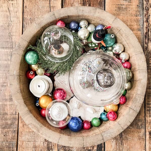 Antique wooden bowl with vintage shiny brite ornaments and bottle brush trees under cloches