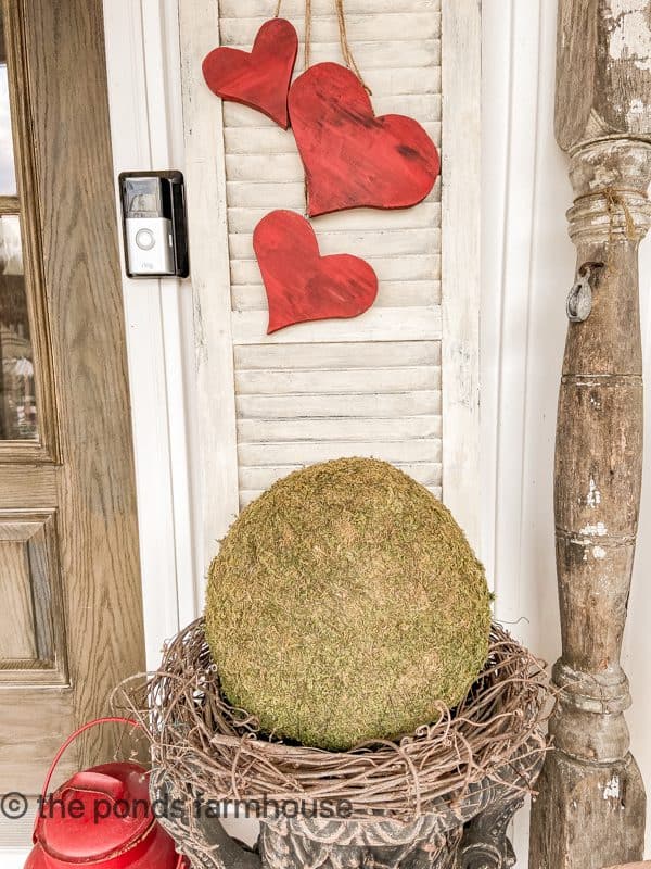 Large moss ball on a grapevine wreath is large urns.  DIY Wooden heart swag. on shutter.