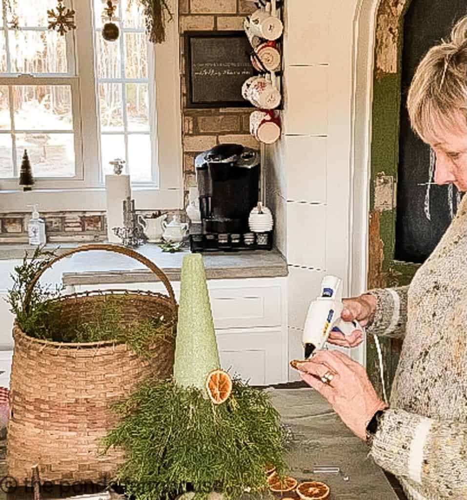 Attach dried orange slices to the cedar for a farmhouse style Christmas Topiary.  