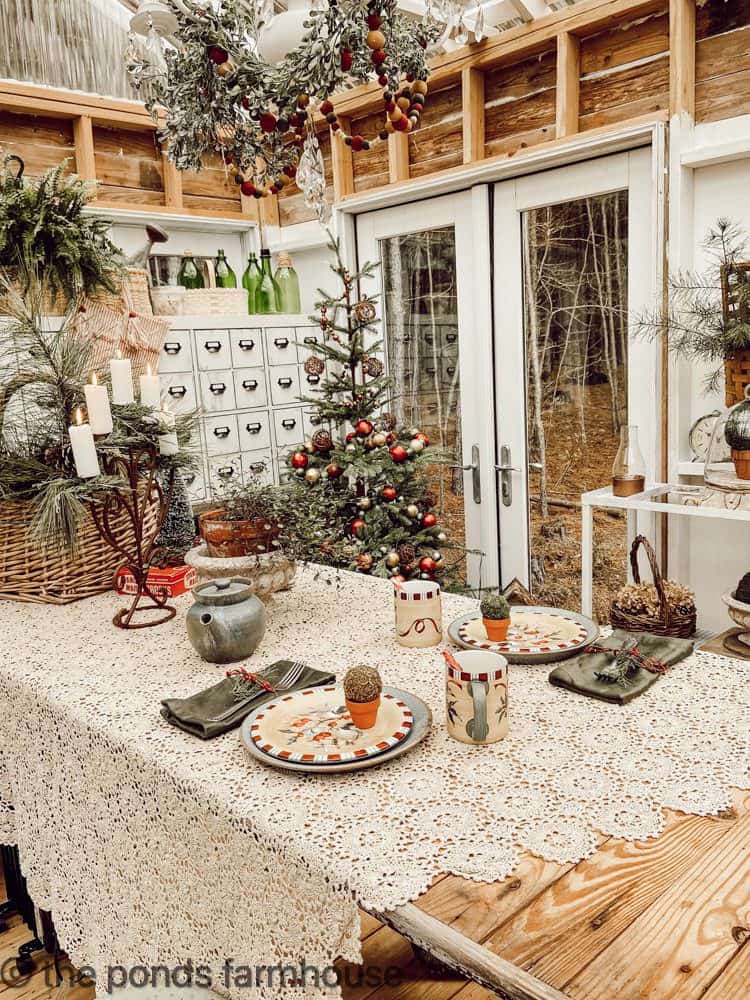 TAble set for two in DIY Greenhouse with vintage lace tablecloth and Christmas tree.