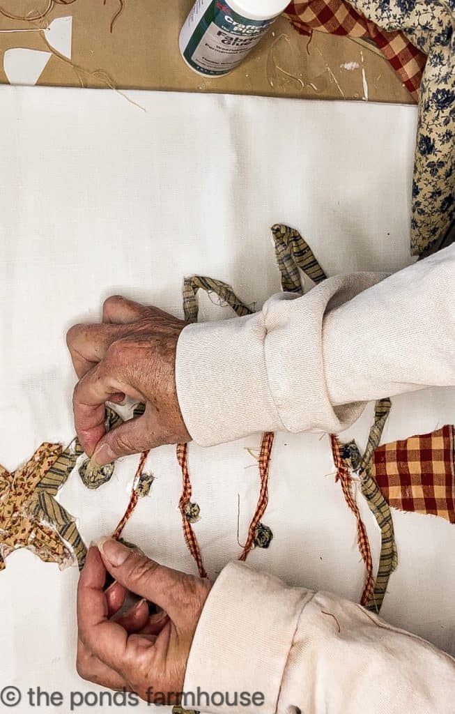 Attaching cloth to Christmas tree pillow.