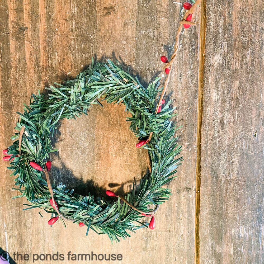 twist the berry garland around the candle ring made from Dollar Tree cedar ties.  