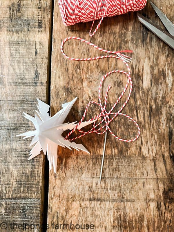 Use red and white baker's twine to string the diy paper Christmas trees together