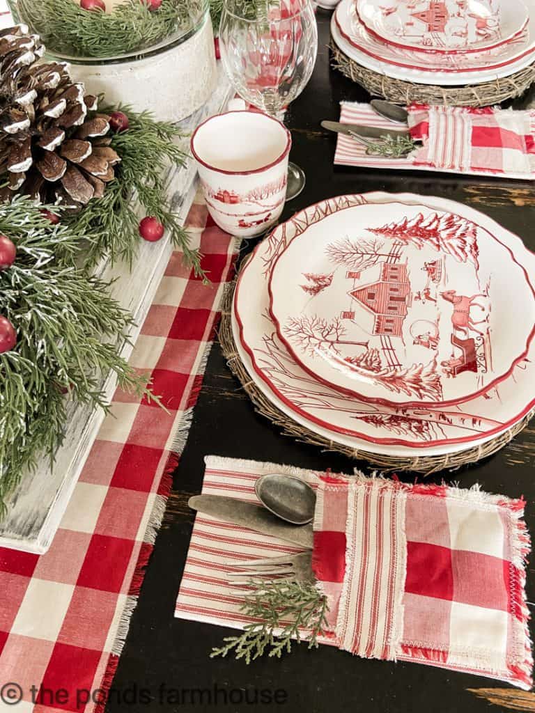Beautiful Farmhouse Style Christmas Tablescape with red and white dishes, table runner and napkins.