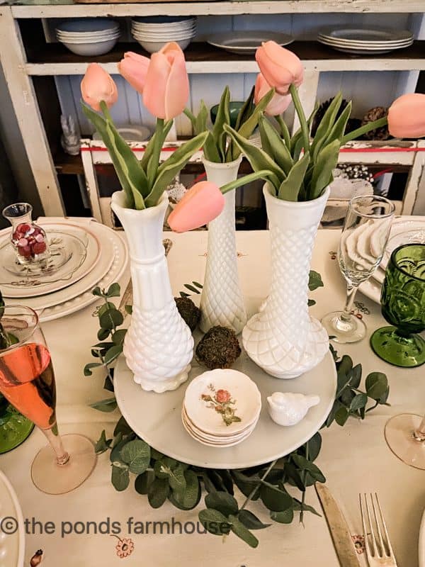 pink tulips in a trio of vintage milk glass vases on cake plate for centerpiece