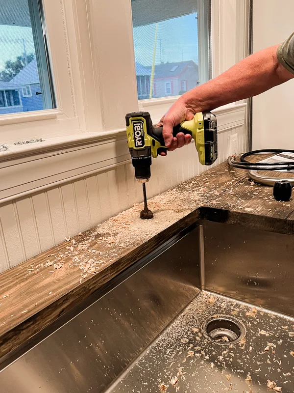 Drilling a hole for the faucet installation in the kitchen countertop.  Budget DIY Kitchen Renovations