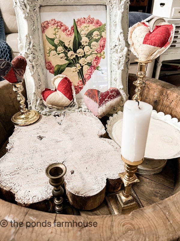 See up a Valentine's Day Vignette in a wooden bowl with old quilt hearts and a printable image in a vintage frame.