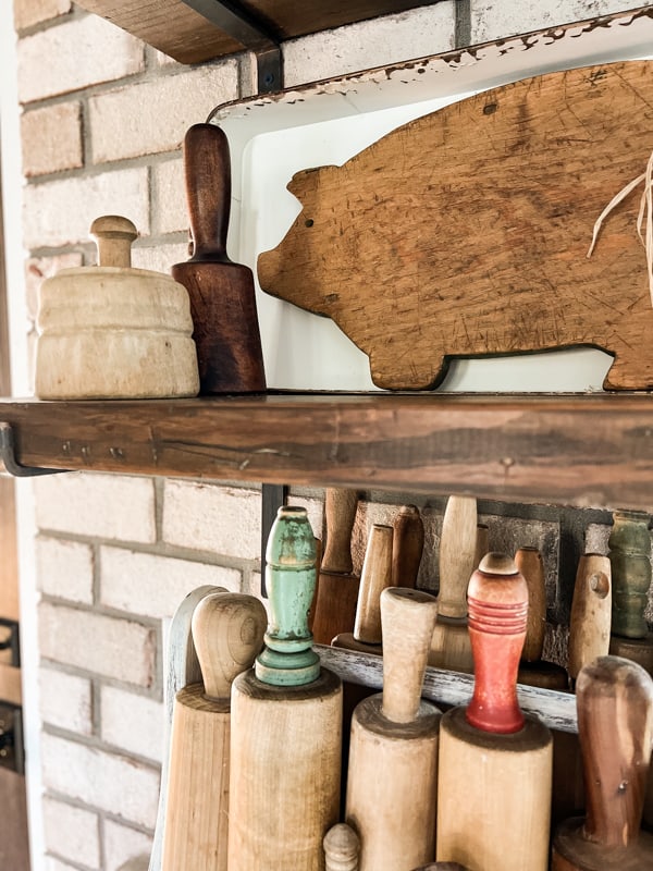 Wooden Vintage pieces like smashers, cutting boards, rolling pins and butter mold fill open shelves in farmhouse. 