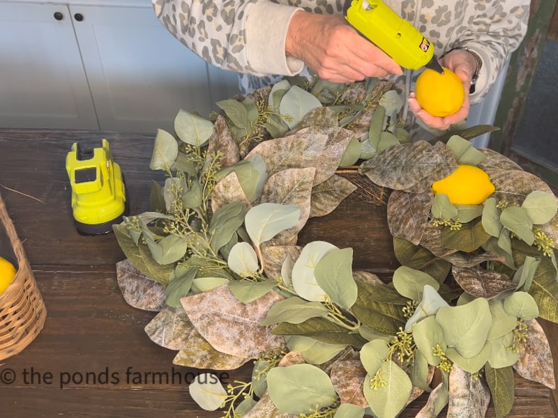 Using Hot Glue to attached lemons for DIY Spring Wreath Ideas.  Repurpose old wreath 