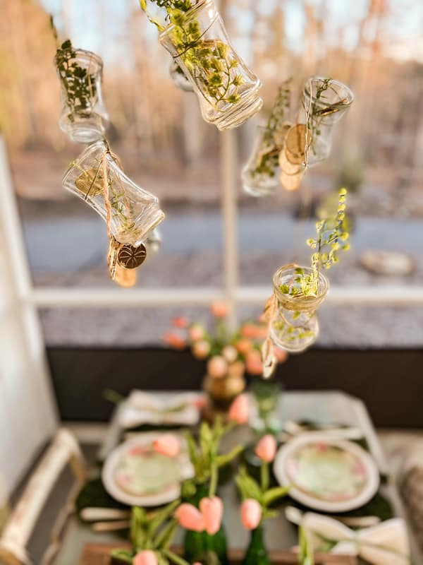 Mini vases with St Patrick’s Day decorations hanging from DIY Light fixture over St. Patty's Day Table Setting.