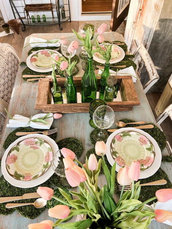 St Patrick’s Day Tablescape. Vintage floral plates with moss place mats, tulips and green bottle for dinner table.