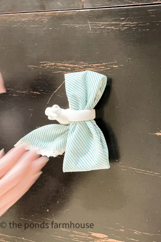 How to Fold a napkin into a bow tie - fluff the napkin and shape the bow tie. Bunny Napkin Ring with blue strip napkin.