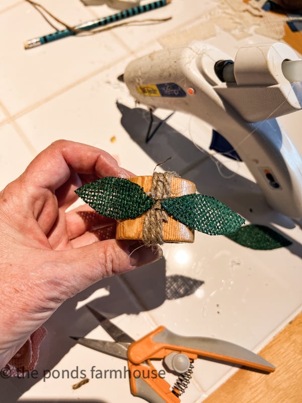 DIY Burlap Napkin Rings with leaves added to jute twine on the wood napkin ring.