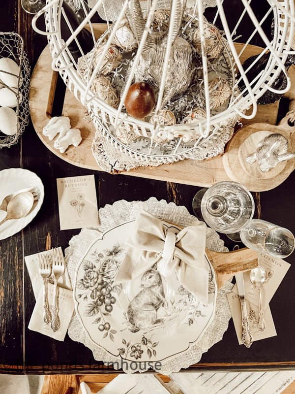 Easter Brunch Table Setting.wooden platter, Pewter bunnies. Metal cage on the dining table. with bunny dishes