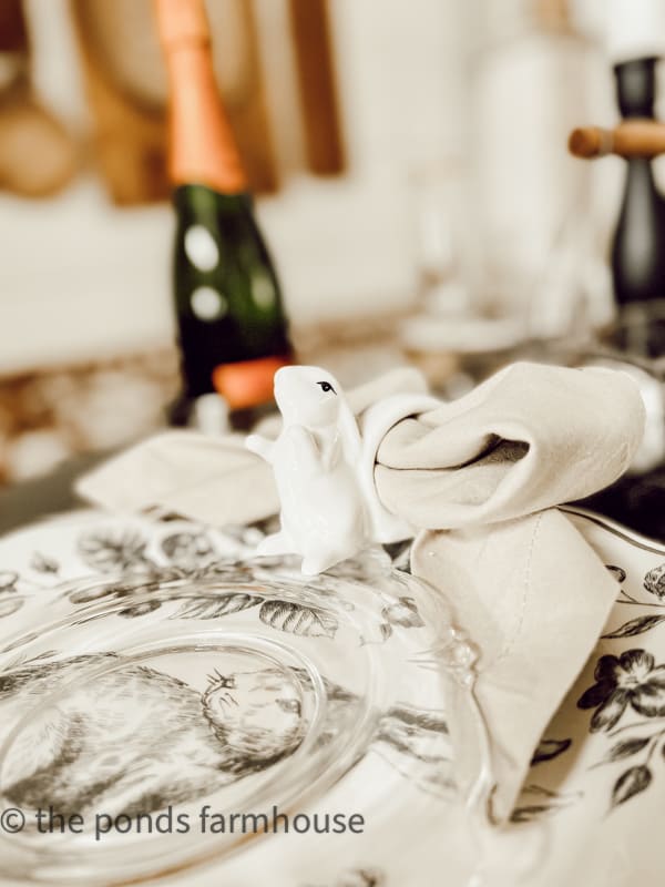 Bunny napkin ring with bow tie napkin fold on black and white bunny plate with clear dessert plate. 