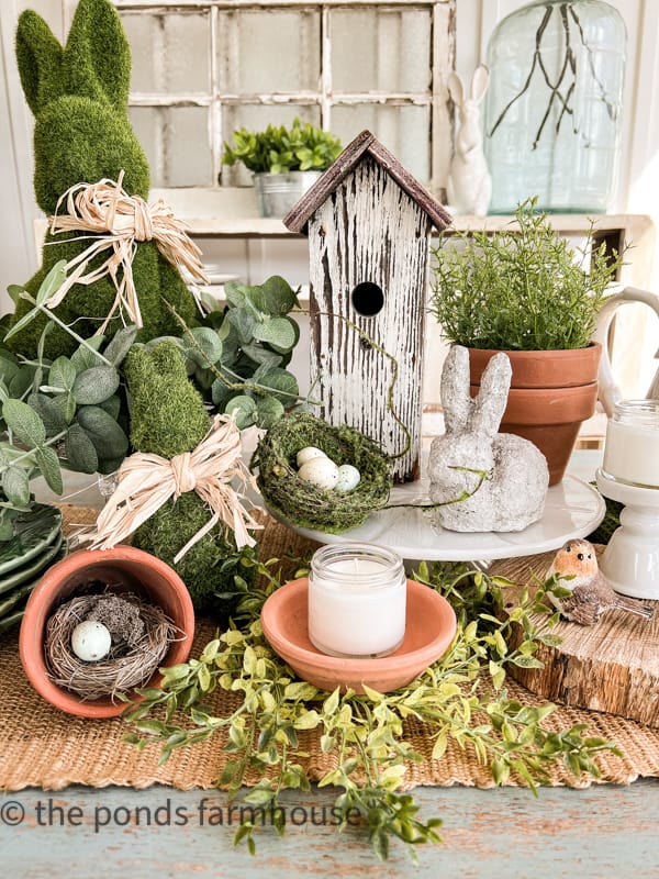Easter Table Centerpiece Ideas. Using bird house and moss Easter Bunny with Easter eggs in bird nest.