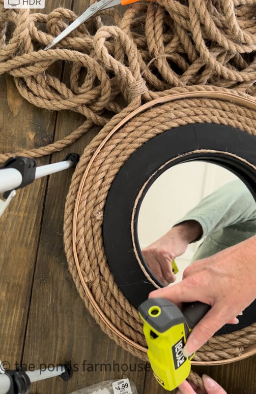 Using hot glue to attach rope hanger to the DIY Nautical Mirror
