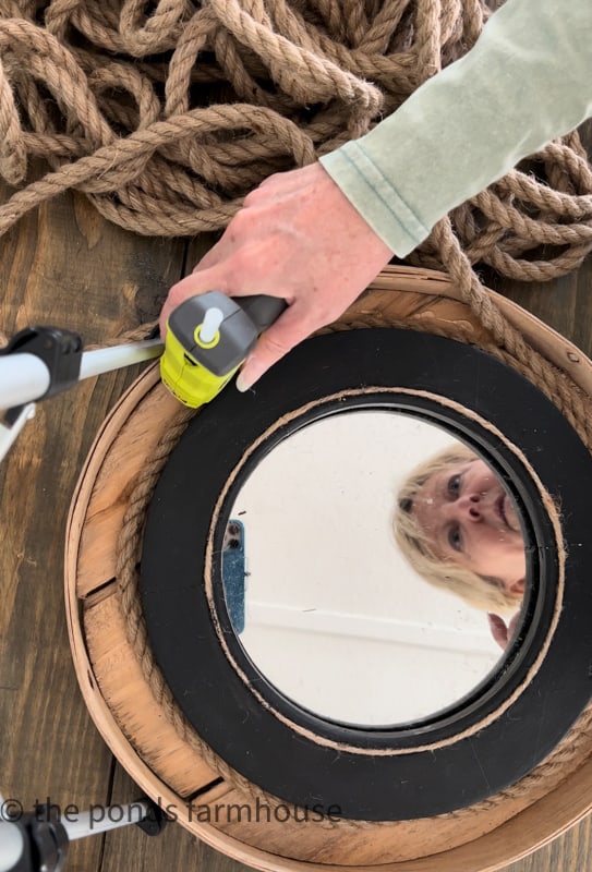 Use Hot glue to attach rope around the mirror to make a DIY Nautical Mirror with Rope