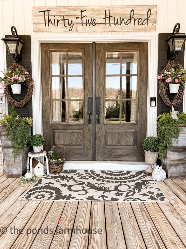 Farmhouse Porch Decor for Spring. Front door with large planters with hanging basket and wreath.