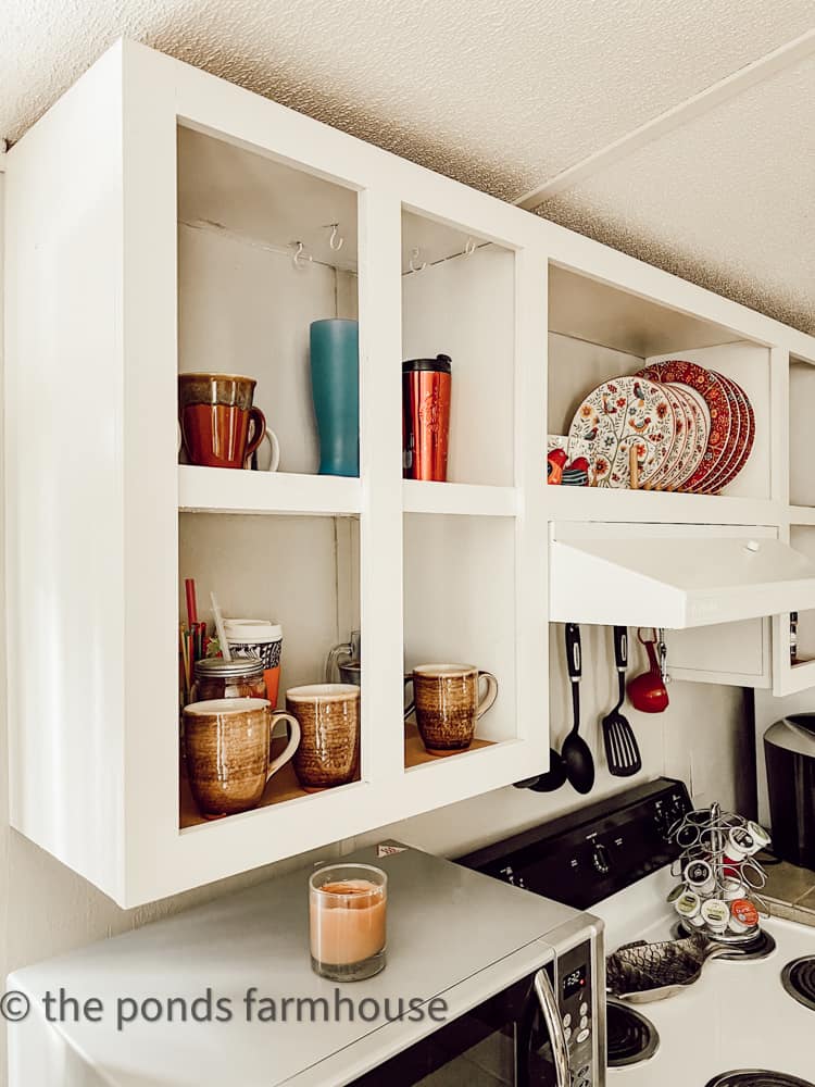 Easy Access to Kitchen Utensils with open shelves painted white with cups and dishes in guest cottage.