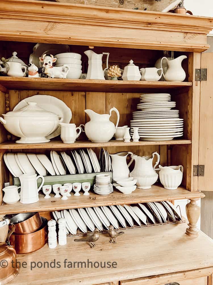 All white dishes in cabinet.  Antique and Thrift store ironstone in a honey pine antique hutch.