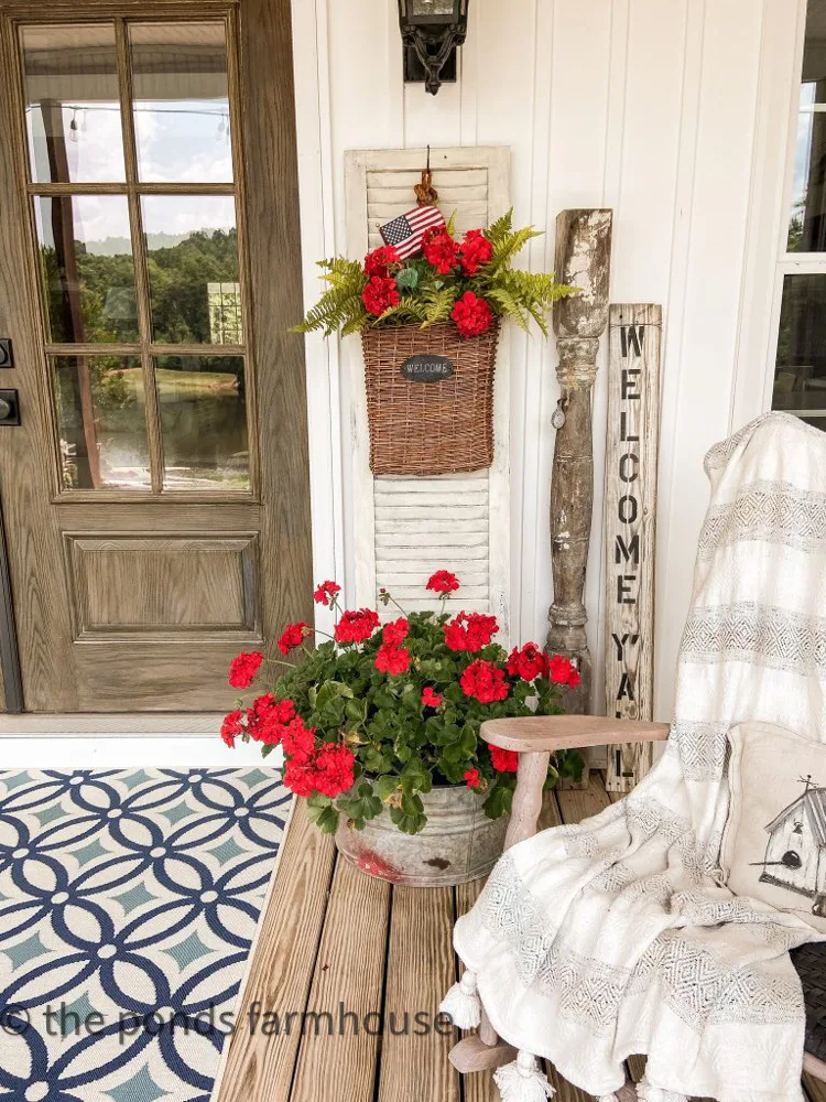 Front Porch Patriotic Decor with red geraniums in galvanized tub and blue and white rug.