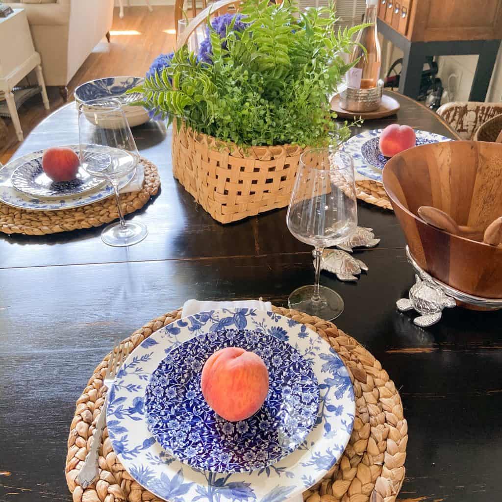 Country Chic Summer Table with fresh peaches on blue and white dishes.  Basket filled with fern and hydrangeas.