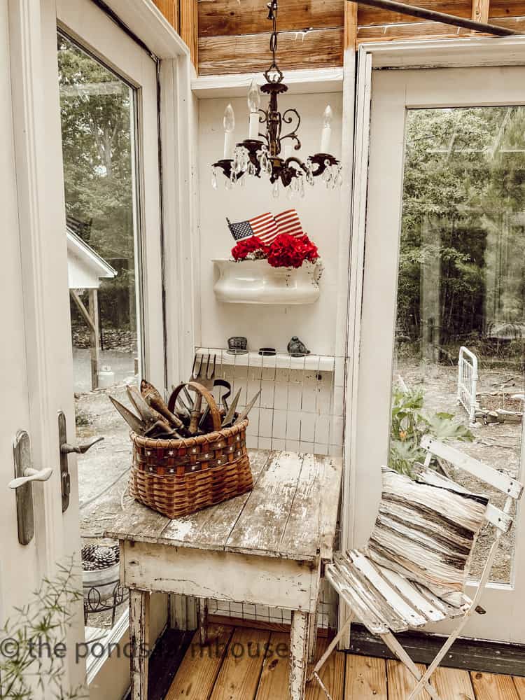 Greenhouse with chandelier and ironstone planter filled with flowers and flags