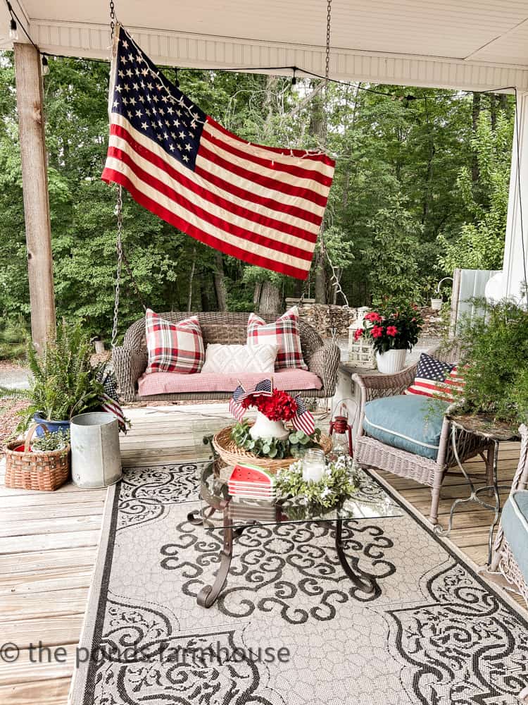 Farmhouse front Porch seating area with flower container gardens for 4th of July outdoor decor.