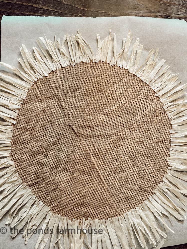 Add raffia pieces to the edges of the round burlap placemat, rarria added to luau placemat.