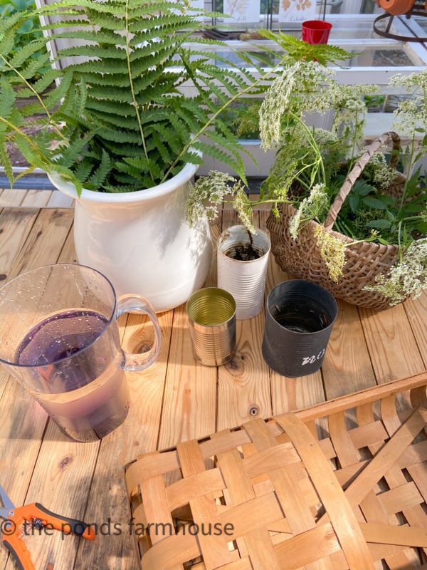 Use tin cans to hold flowers and ferns and keep them watered inside a basket floral display