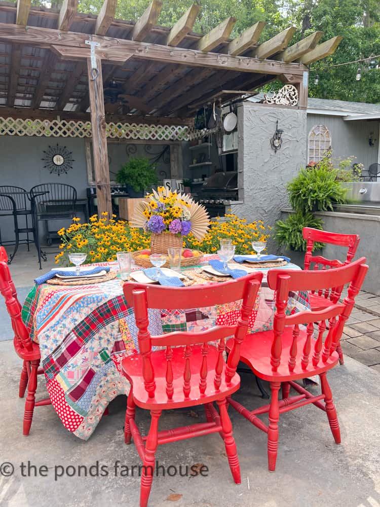 Red Vintage Chairs with vintage quilt for a table cloth make a great backyard B B Q or outdoor B B Q setup