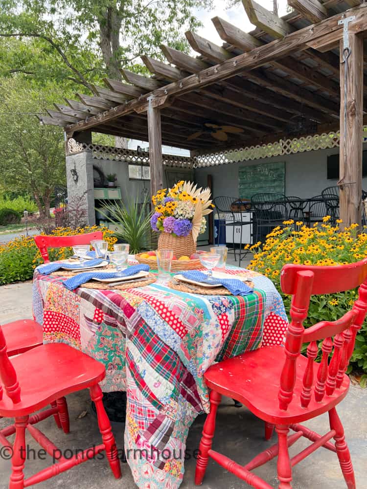 Vintage quilt table cloth and vintage red chair set the tone for a backyard B B Q, outdoor cookout, outdoor B B Q  
