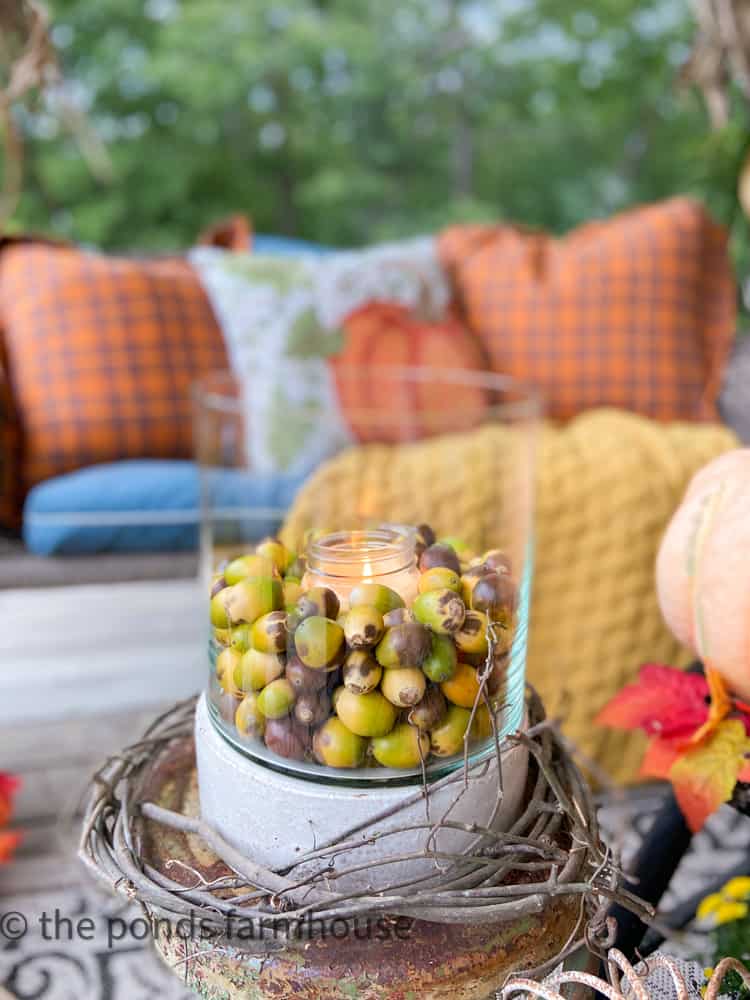 Vintage Hurricane Candle Holder with acorns on fall farmhouse porch.
