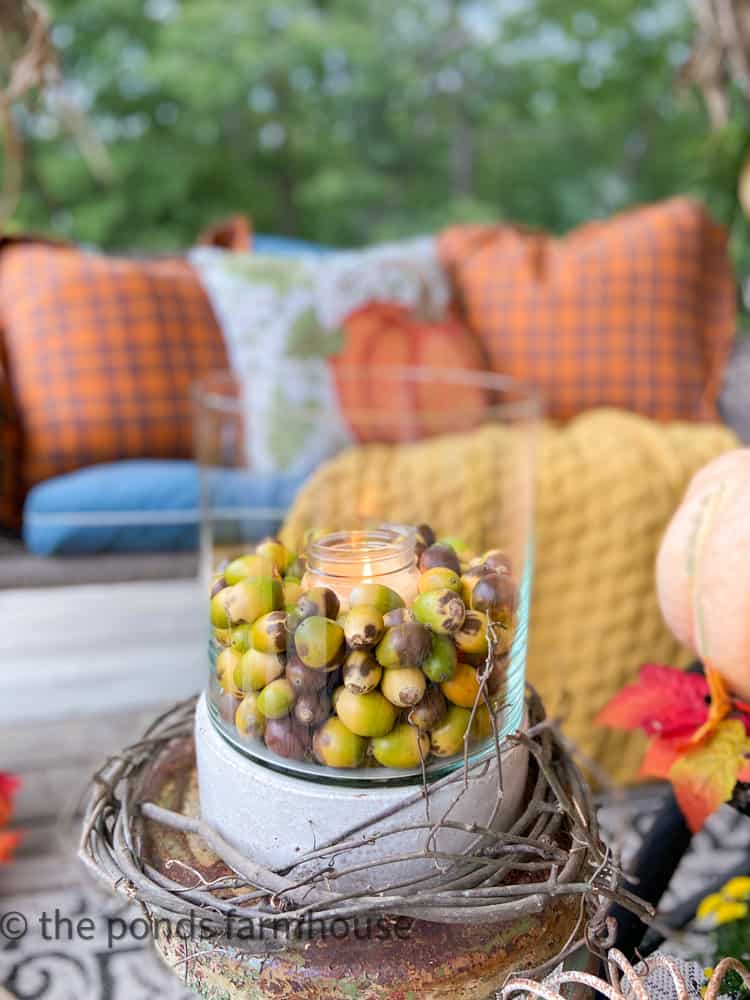 Thrift store glass container with candle and foraged acorns surrounded by foraged grapevine.