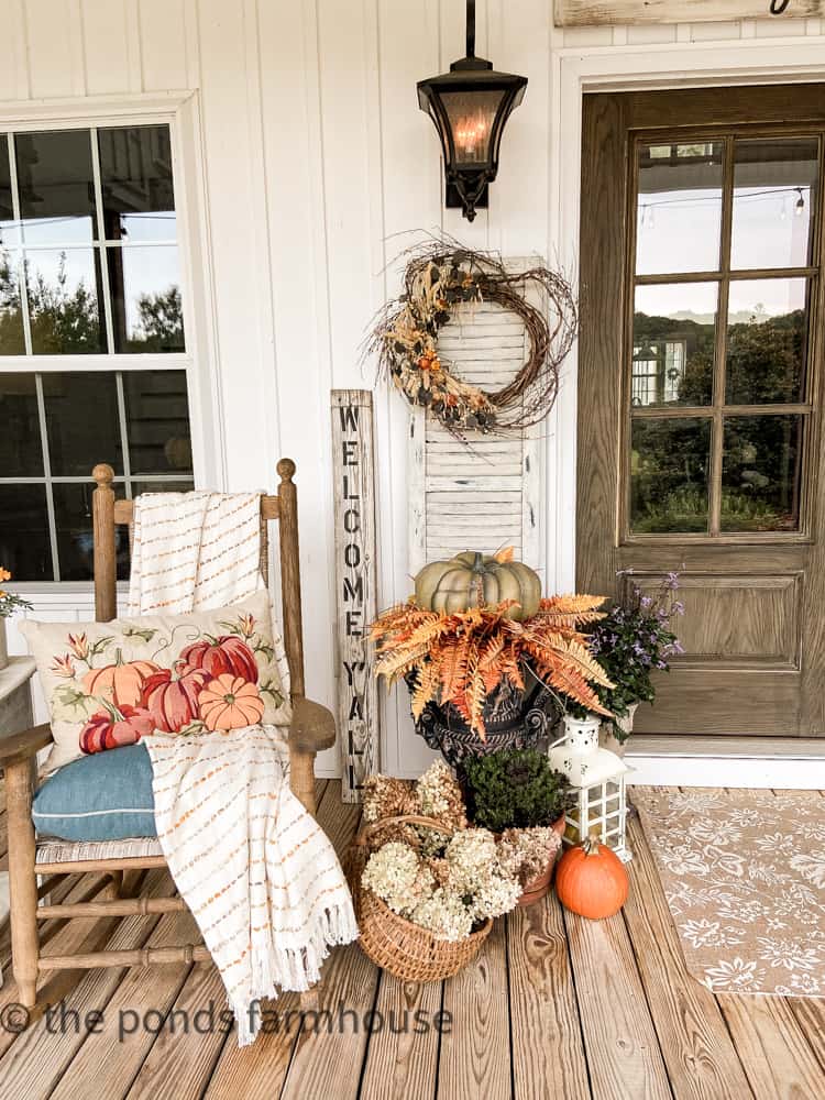 Planter for Fall Farmhouse Porch Tour filled with fall foliage and pumpkins and rocker with fall throw blanket and pillow
