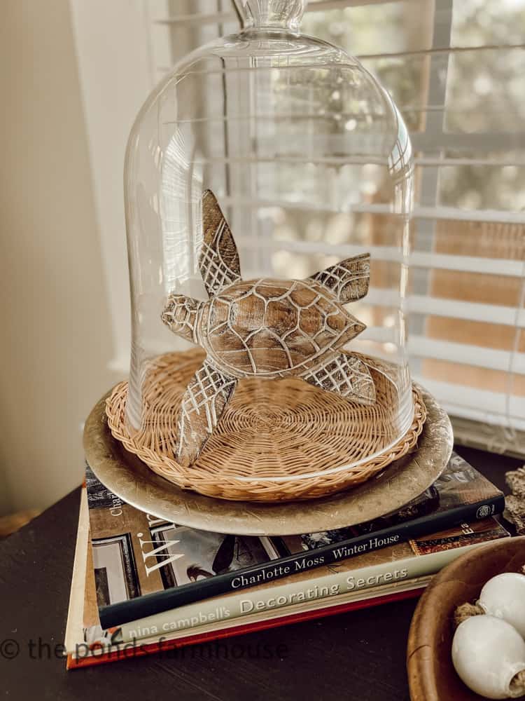 A wooden sea turtle under a cloche for coastal decor ideas. Beach decor. 