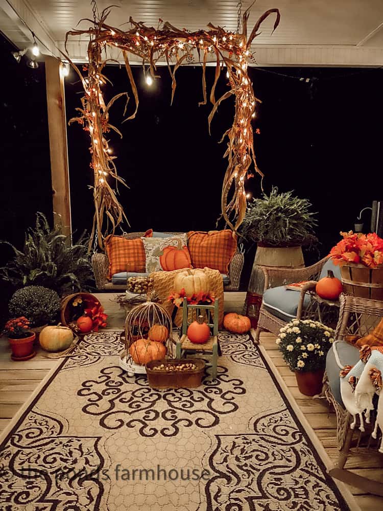 Farmhouse Porch swing wrapped with corn stalks and twinkle lights decorated for fall.  