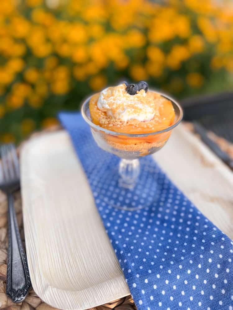 blue napkin over bamboo plate with parfait glass.  Dreamy Peaches & Cream Icebox Dessert Recipe. Refreshing peach deserts