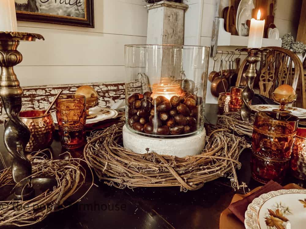 Thrifted vintage candle holder with acorns and grapevine wreaths for a Thanksgiving table centepiece.
