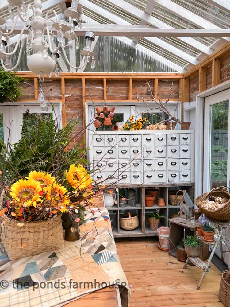 DIY Apothecary Cabinet and Greenhouse decorated for Sunflower Season with baskets and clay pots. 