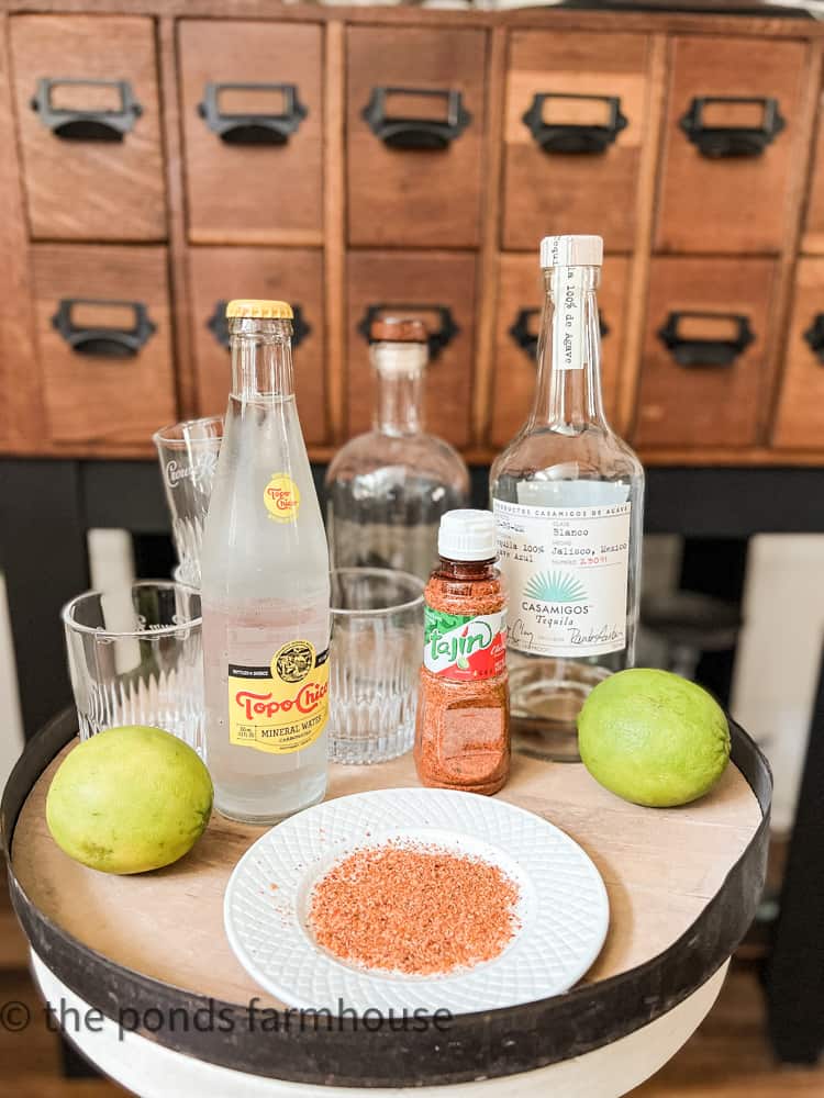 Bar set up with tequila, topo chico, limes, tajin seasoning and cocktail glasses.  