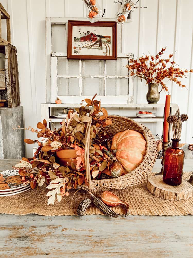 Fall Table Decorations with thrifted basket filled with autumn pumpkins on screen porch