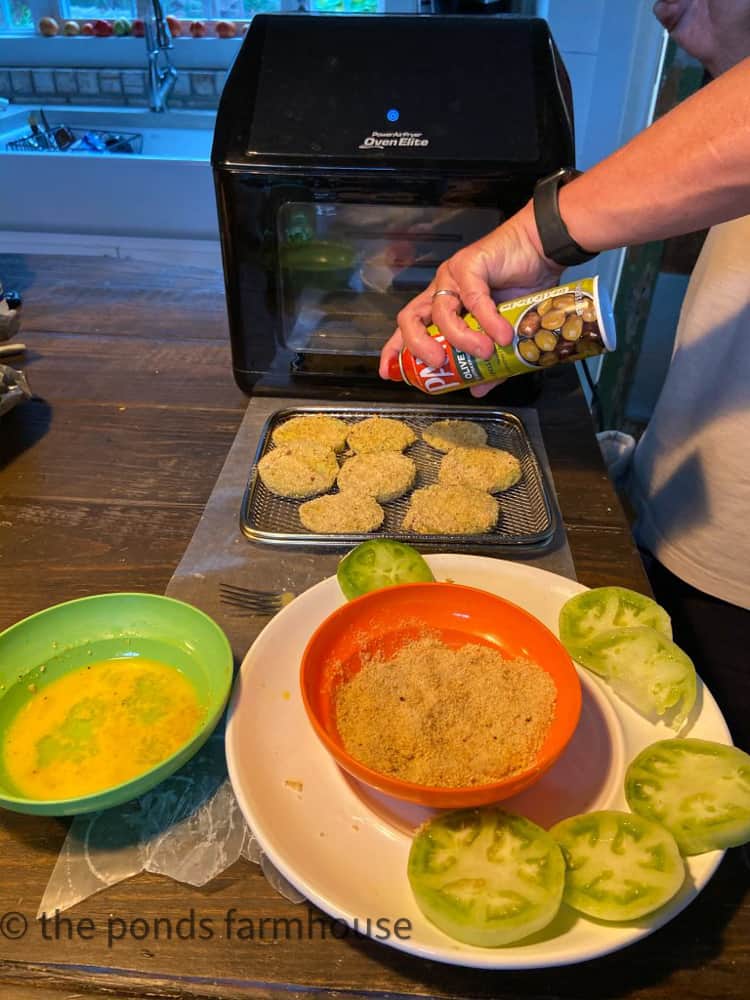 Spraying bread coated green tomatoes in prep for air frier.  